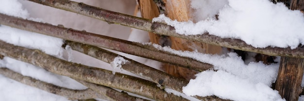 Besneeuwde winterseizoen in de natuur verse ijzige bevroren sneeuw en sneeuwvlokken bedekt houten takken stokken hek op ijzige winterdag in bos of tuin koud weer kersttijd banner