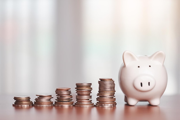 Foto besparing spaarvarken met stap van geld munten op de houten tafel