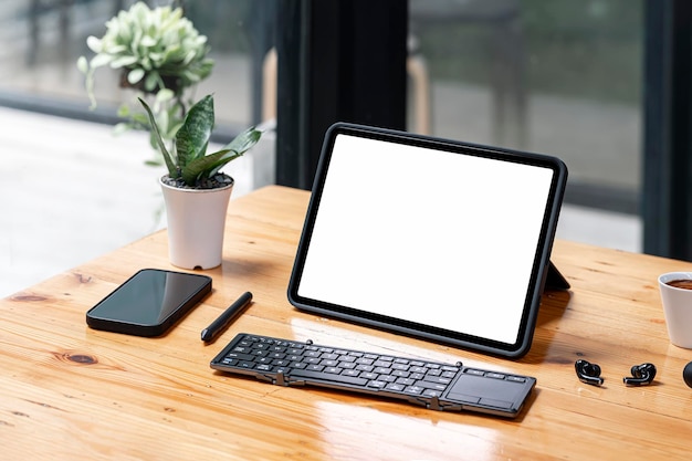 Bespotten van draagbare tablet met toetsenbord en gadget op houten tafel in caféruimte.