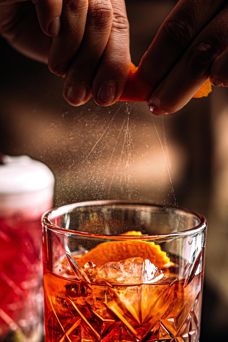 Foto besprenkelende negroni cocktail van sinaasappelschil