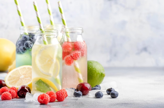 Bessen en citrusvruchten doordrenkt zomer koude dranken in glazen flessen op grijze stenen tafel achtergrond