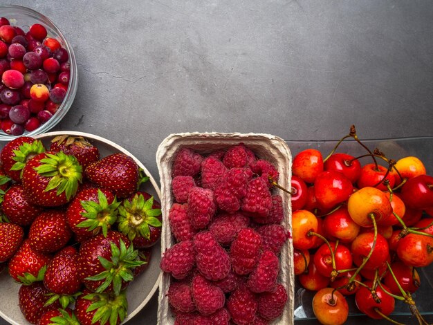 Bessen op betonnen achtergrond Zomer of lente Biologische bessen Aardbeien Frambozen Kers Veenbessen Landbouw Tuinieren Oogstconcept