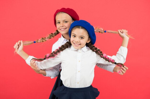 Best braided hairdo Small girls being proud of long braid hairdo on pink background Little kids holding plait hairdo Children need new hairdo in hair salon