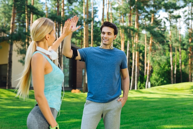 Best friends. Joyful positive people giving each other a high five while coming after the workout