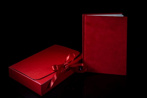 Best gift for men Man gift concept Red notebook with red gift box on black background Copy space Valentines day wedding birthday and special occasion gift concept Copy space for text