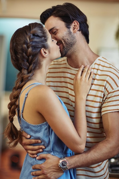 The best kisses are unexpected Shot of an affectionate young couple kissing in their kitchen at home