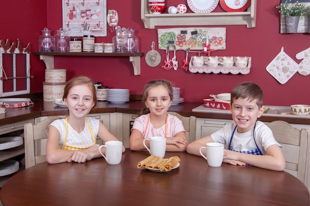 Best little friends resting in kitchen and holding cups in their hands and drinking tea and looking