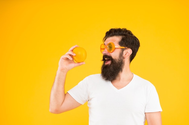 Best orange snack Happy guy taking snack break on yellow background Hipster looking at healthy organic snack Snack that gives you energy copy space