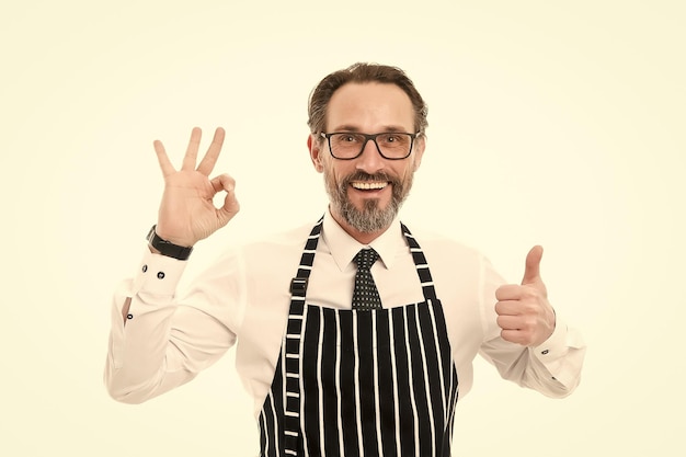 Best and perfect best mature male cook isolated on white confident chef in apron perfect cooking in kitchen bearded man baker in glasses catering business thumb up and ok gesture be the best