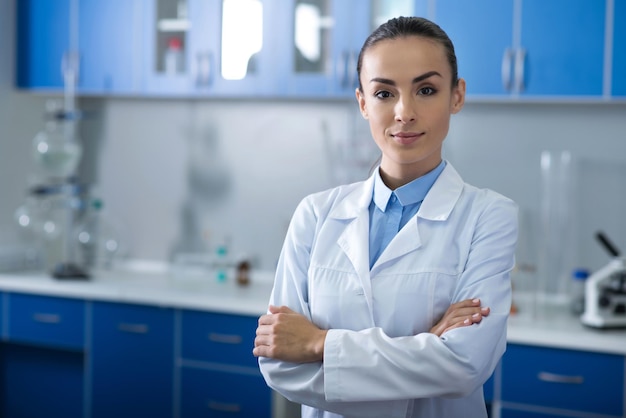 Best scientists Young pretty selfconfident scientist standing in the lab looking straight and holding her hands crossed