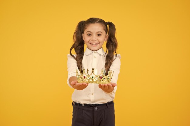 Best student prize reward happy small child giving out crown reward on yellow background little schoolgirl smiling with jewel reward reward success