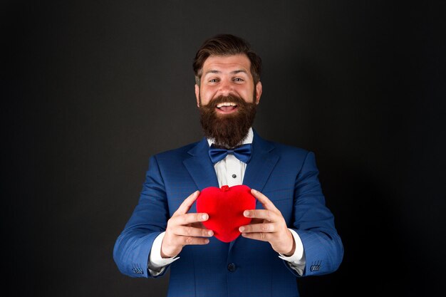 Best wishes from sincere heart Businessman in bow tie Heart symbol aesthetics Valentines day holiday Love and relations Wedding day Bearded man groom in formal suit Health care Heart in hands