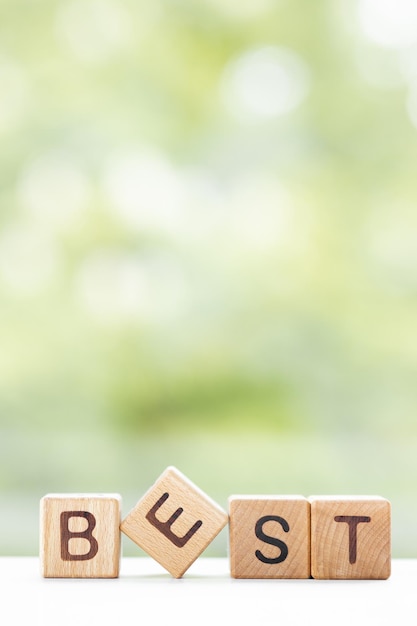 Best word is written on wooden cubes on a green summer background Closeup of wooden elements