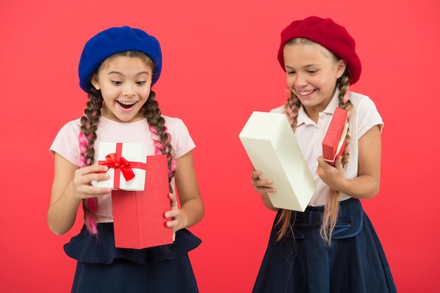 Beste cadeaus voor kinderen Kleine meisjes in schooluniform en baretten houden geschenkdozen vast Kinderen enthousiast over het uitpakken van geschenken Kleine schattige meisjes ontvangen vakantiegeschenken Breng geluk aan kinderen