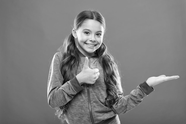 Beste keuze Kid blij lachend gezicht laat iets zien op open palm kopie ruimte Meisje demonstreert product Reclame en commercieel concept Product promoten voor kinderen Product lanceren voor kinderen
