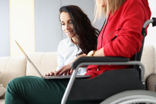 Beste vrienden brengen samen tijd door met het kijken naar film op laptop vrouw in rolstoel houdt apparaat op schoot