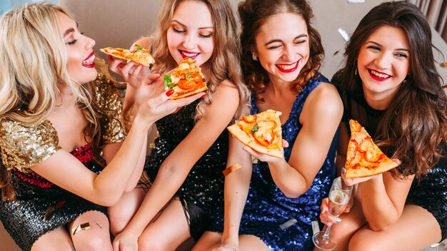 Beste vrienden die rondhangen, plezier maken, lachen. Jonge dames die elkaar voeden met heerlijke pizza.