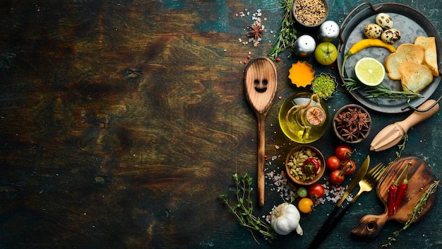 Bestek op een zwarte stenen tafel met groenten en kruiden Voedsel achtergrond Bovenaanzicht Rustieke stijl