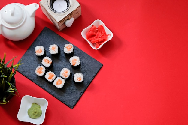 Foto bestel bezorging sushi-broodjes met japans eten terwijl u thuis in quarantaine blijft. huisvorm op rode achtergrond met exemplaarruimte