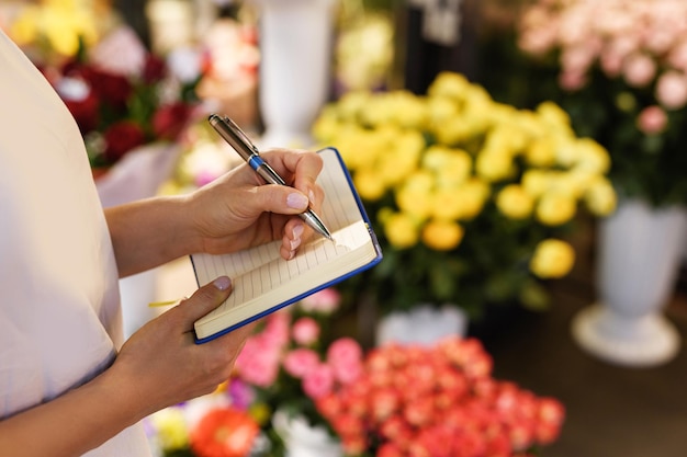 Bestellingen in bloemenwinkel. vrouw bloemist maken van aantekeningen in haar notitieblok.