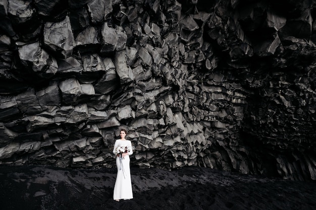 Bestemming ijsland bruiloft de bruid in een witte zijden jurk met een boeket in haar handen staat op