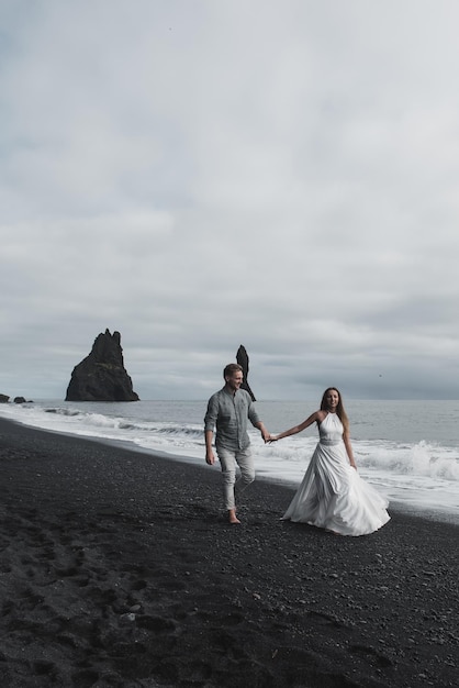 Bestemming IJsland bruiloft. Een bruidspaar loopt langs het zwarte strand van Vic.