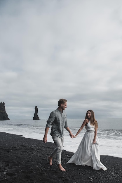 Bestemming IJsland bruiloft. Een bruidspaar loopt langs het zwarte strand van Vic.