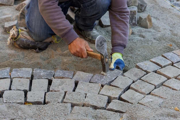 Bestrating bestrating met granieten stenen, werknemers die industriële kasseien gebruiken voor bestrating weg