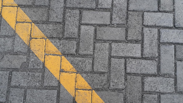 Foto bestrating plaat grijze stedelijke straat met diagonale gele lijnen wegmarkeringen steen tegel textuur achtergrond