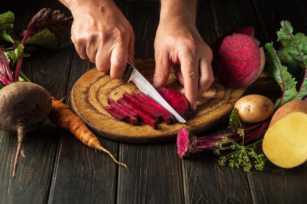 Beta vulgaris of rode biet snijden door de handen van een kok op een snijplank om heerlijke borsjt te bereiden