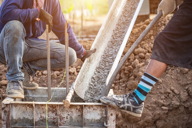 Beton gieten in stalen kist voor funderingspijler tijdens woningbouw