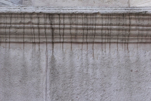 Betonnen grijze muur met verticaal donkere waterlijnen verticaal