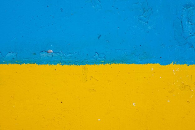 Betonnen muur geschilderd in geel en blauw zoals de Oekraïense vlag, het land van het slachtoffer van de agressor