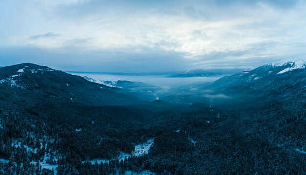 Betoverend uitzicht op prachtige bergwanden bedekt met sneeuw en mist op een bewolkte winterdag