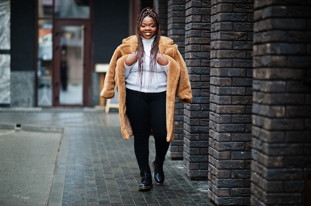 Betoverende Afro-Amerikaanse vrouw in warme bontjas poseren op straat.