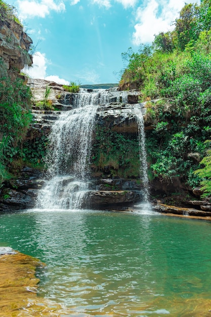 Betoverende verticale opname van een waterval in een jungle vol kliffen en prachtige groene bladeren