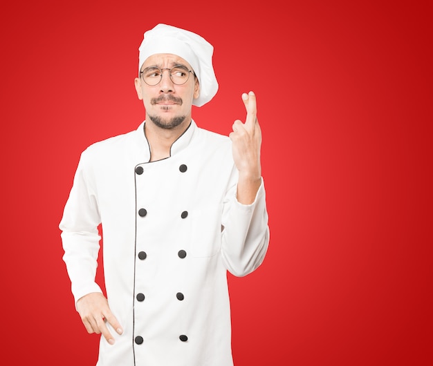 Betrokken jonge chef-kok die een gekruist vingersgebaar doet