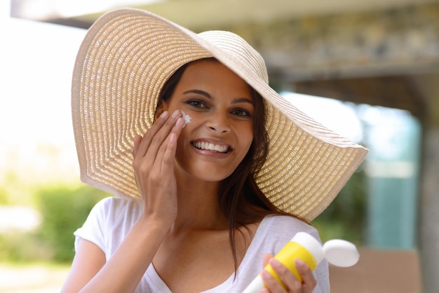 Better safe than sorry Een aantrekkelijke jonge vrouw die zonnebrandcrème op haar gezicht aanbrengt