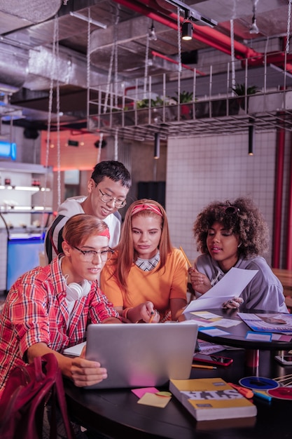 Better together. Charming girl sitting between her classmates while staring at computer