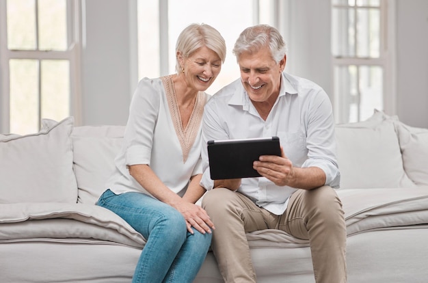 Better together. Shot of a elderly couple using a tablet at home.