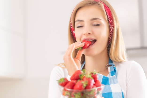 新鮮なイチゴの一口の味を楽しむ美しい若い女性