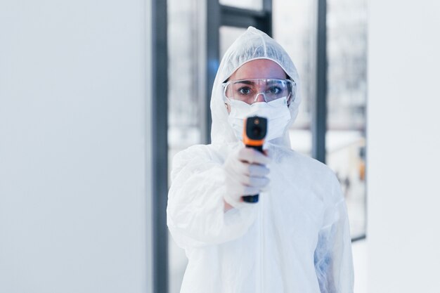 Bevat infraroodthermometer. Portret van vrouwelijke arts wetenschapper in laboratoriumjas, eyewear verdediging en masker