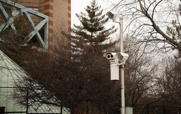 Beveiligingscamera gemonteerd op een gebouw met uitzicht op een drukke straat terwijl camera langs de weg op een paalkap