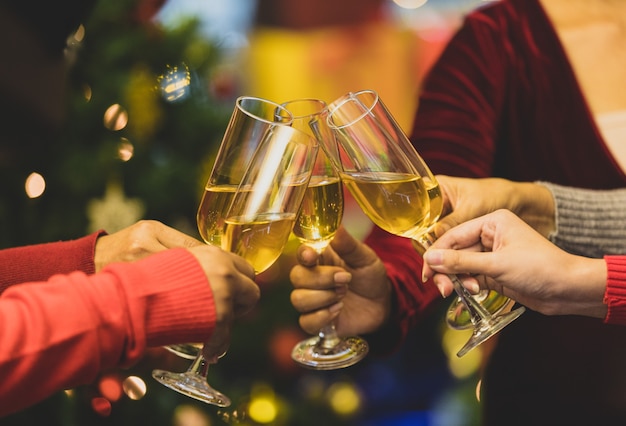 Beverage glasses clinking moment by cheerful woman friends on sweater as enjoy celebrating happy relationship at delightful event of Chirstmas night party. Add some noise to fit vintage-style image.