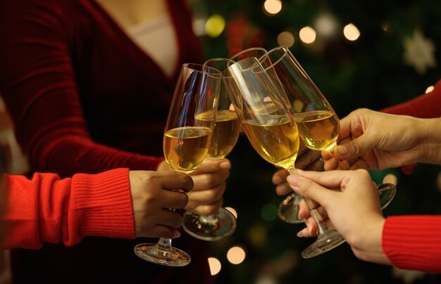 Beverage glasses clinking moment by cheerful woman friends on\
sweater as enjoy celebrating happy relationship at delightful event\
of chirstmas night party. add some noise to fit vintage-style\
image.