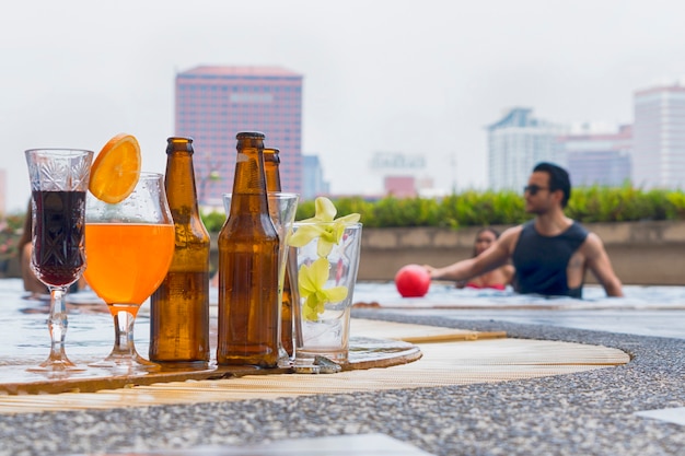 Beverage and juice drink with exotic cocktails and bottle of beer set up on the swimming pool with background