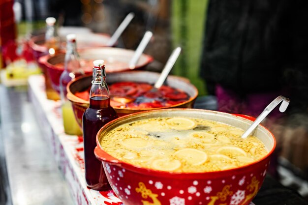 Beverages fruits and berries hot mulled wine in red pots in street food market colorful hot drinks a