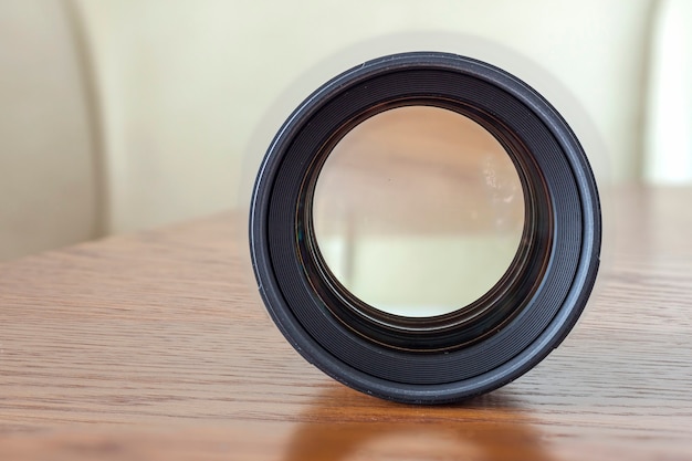 Bevestig de lens van een spiegelreflexcamera close-up met een reflectie op een houten oppervlak.