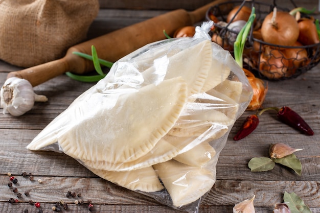 Bevroren chebureks in de zak op een houten tafel met ingrediënten