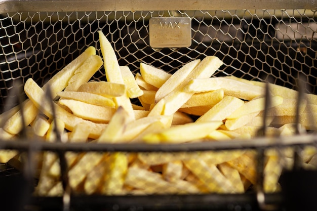 Bevroren frietjes in een frituurmand Halffabrikaat van bevroren aardappelen Voorbereiding op frituren